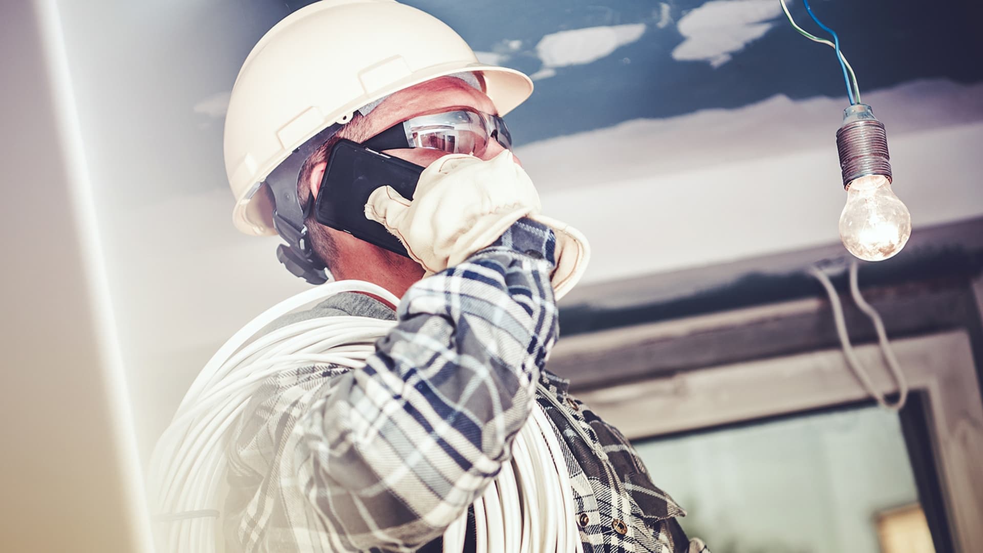 A commercial electrician using his cell phone during project management