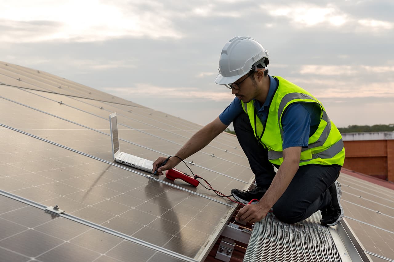 A commercial solar technician on a rooftop with a laptop