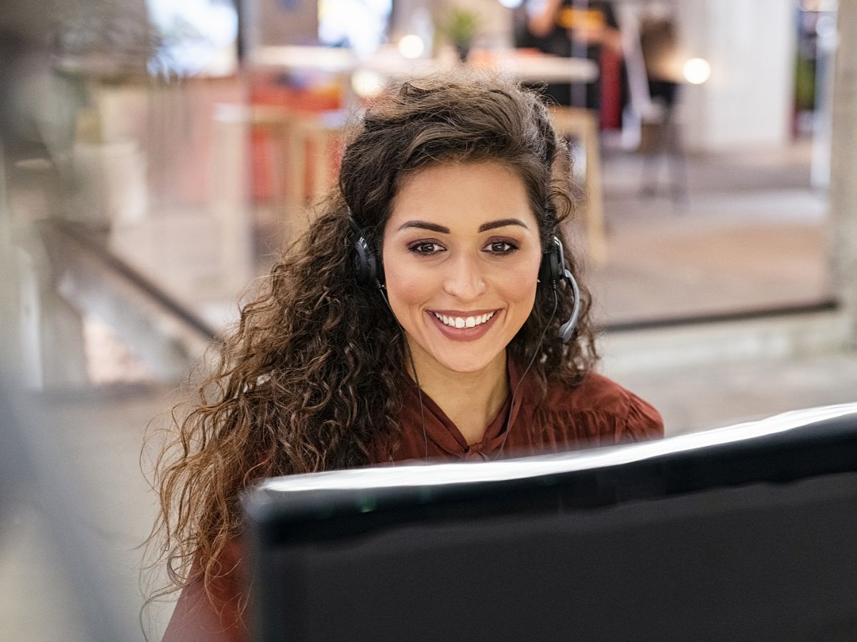 Smiling woman with curly hair working in field service management as a dispatch