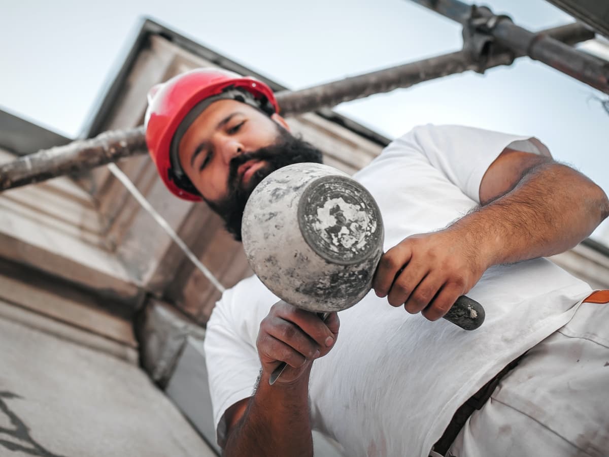 Worker with red helmet mixes concrete.