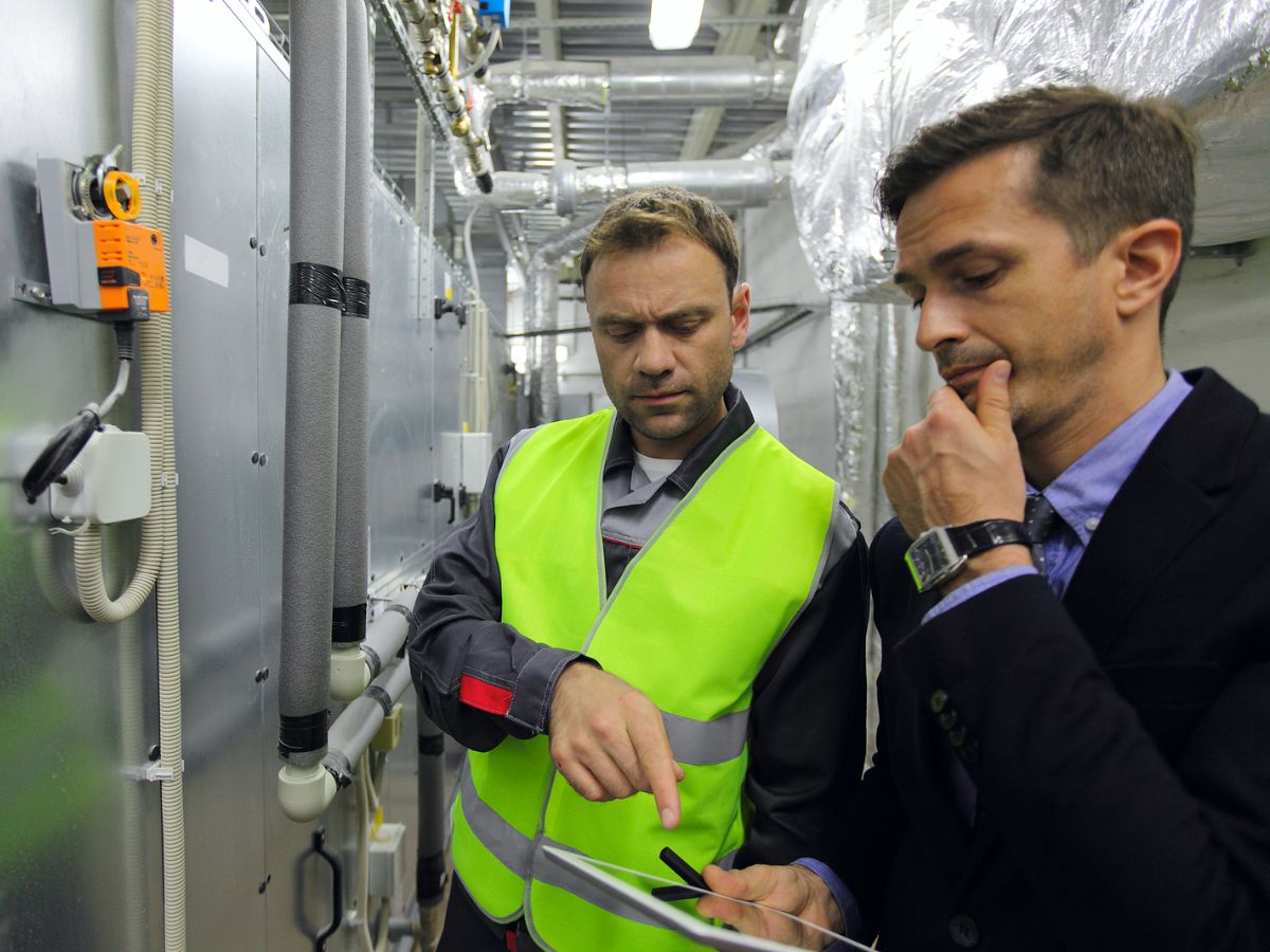 Two people, one in a high-vis vest, looking at a mobile device and using field service management software